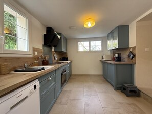 A modern kitchen with a Bosch dishwasher, grey cabinets, a wooden countertop, and a window providing natural light. - CONDOU - LOURDIOS ICHERE (LOURDIOS ICHERE)