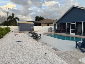 En baghave med swimmingpool, havemøbler og et indhegnet område.