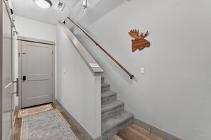 A staircase with a wooden handrail, a grey carpet, and a white door. - The Payette Perch- Pets ok- sleeps 6 (McCall)