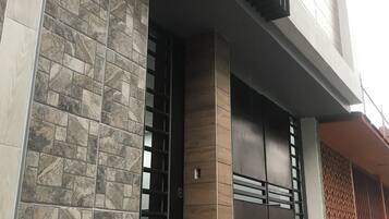 Un bâtiment moderne avec une façade en pierre, une grande porte en bois et un portail en métal.