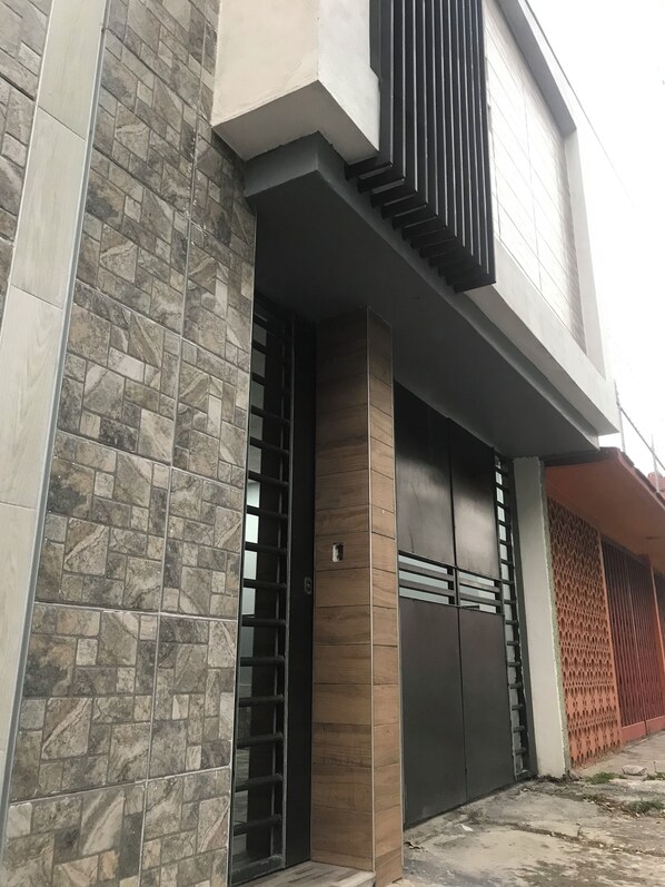 A modern building with a stone facade, a large wooden door, and a metal gate.