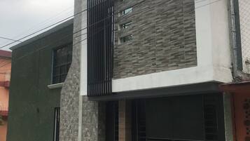 Un edificio moderno de dos pisos con una puerta de garaje, una ventana pequeña y una línea eléctrica visible.