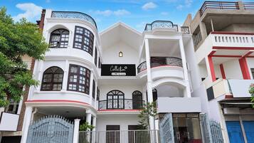 Un edificio de varios pisos con entrada central, balcones y un letrero que indica que cuenta con servicios de OYO.