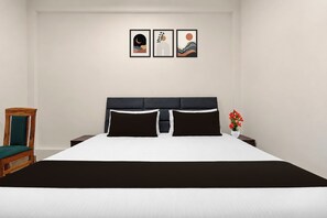 Un dormitorio con una cama, una mesita de noche, una silla y tres cuadros en la pared.