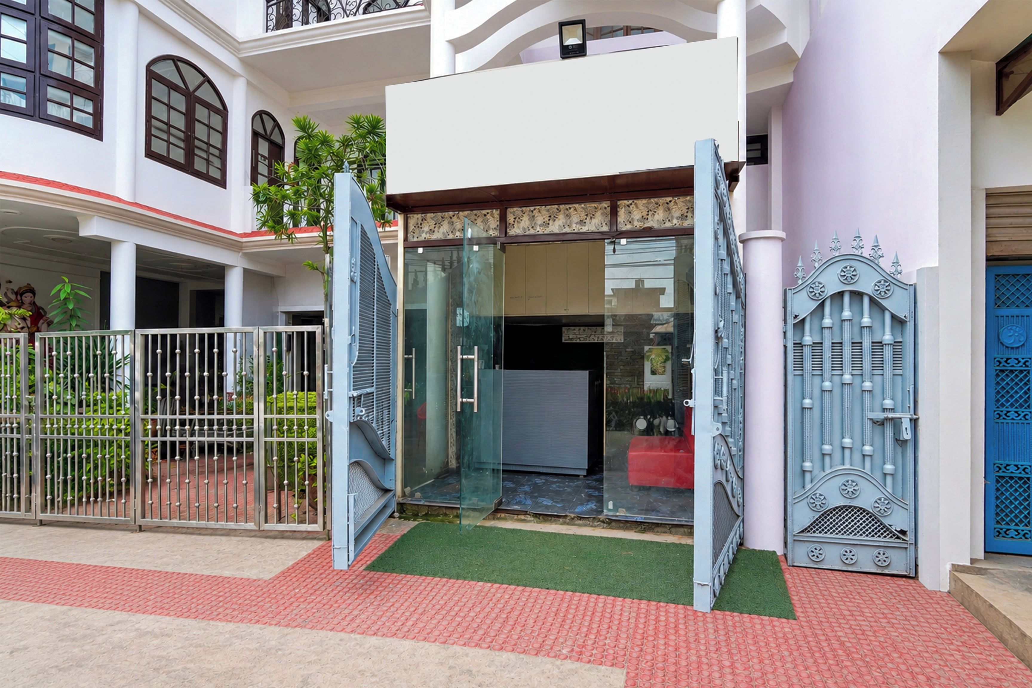 Una entrada cerrada con puerta de vidrio, reja metálica y puerta azul con detalles decorativos.