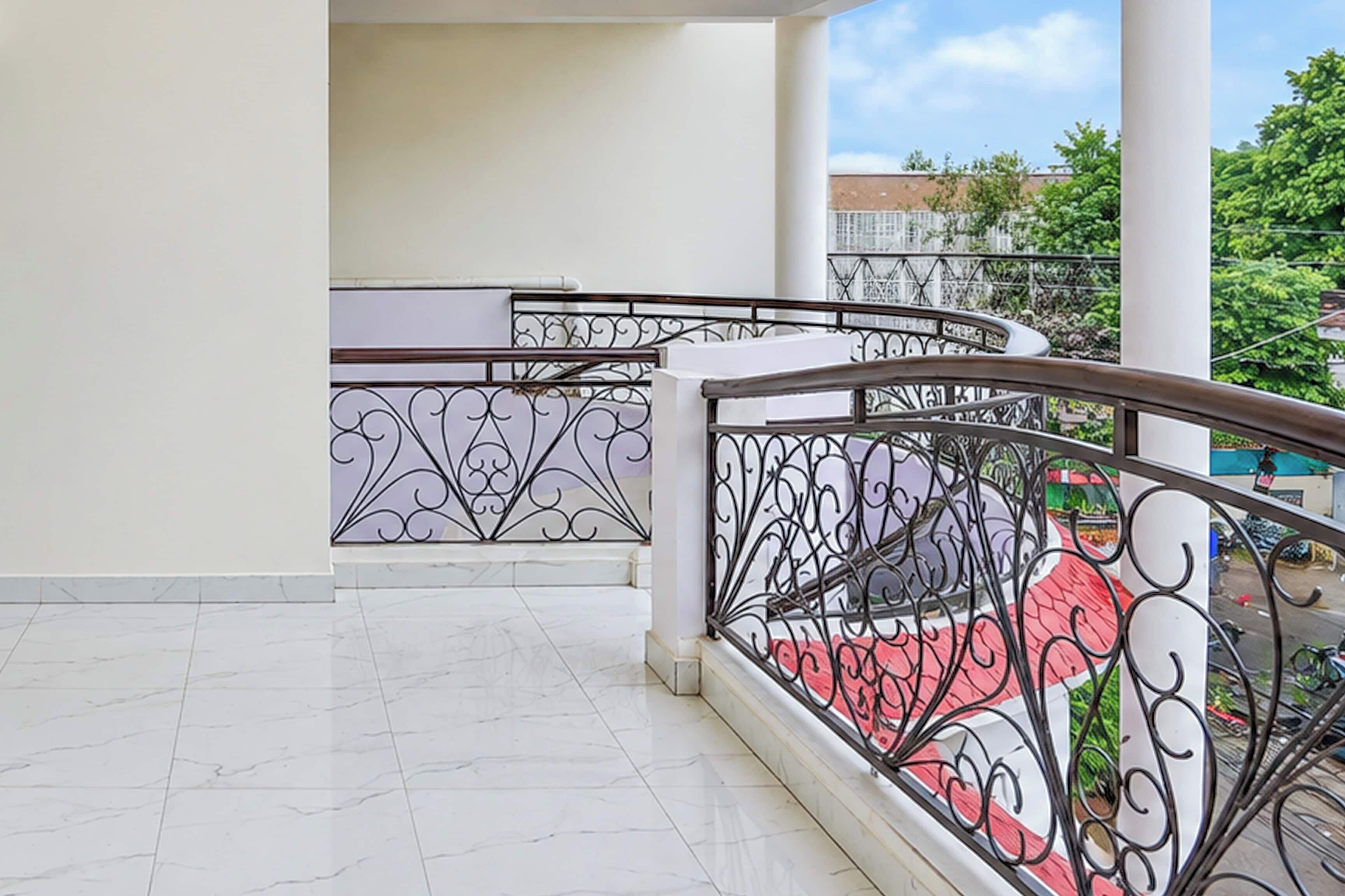A balcony with a white tiled floor and a metal railing with intricate designs.