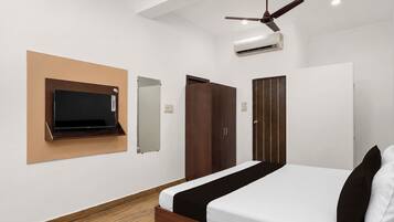 A bedroom with a bed, a TV mounted on the wall, a wardrobe, and a ceiling fan.
