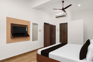 Un dormitorio con cama, televisor montado en la pared, armario y ventilador de techo.