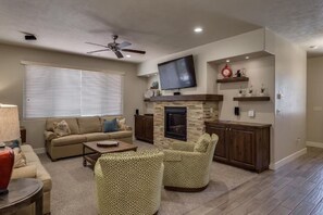 A living room with a sofa, armchairs, a coffee table, a fireplace, a television, and a ceiling fan. - Paradise Village 26, Private Spa, 2 Resorts, and more! (Santa Clara)