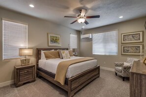 A bedroom with a bed, bedside tables, a ceiling fan, and artwork on the walls. - Paradise Village 26, Private Spa, 2 Resorts, and more! (Santa Clara)