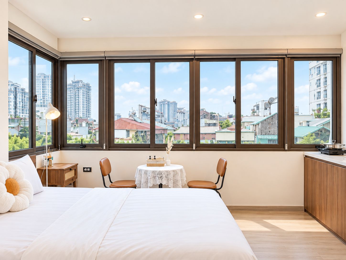 Habitación de hotel con un ventanal grande, una cama, una mesa con una silla y una kitchenette.