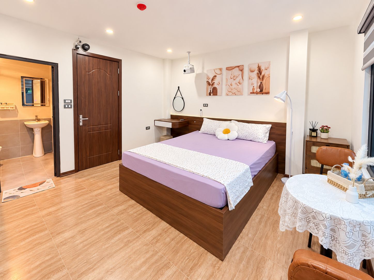 Un dormitorio con una cama de madera, una mesita de noche, una lámpara y una pequeña mesa con objetos decorativos.