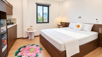 Ein Hotelzimmer mit einem Bett, einem kleinen Tisch, einem Kühlschrank, einem Fenster und einem Badezimmer.
