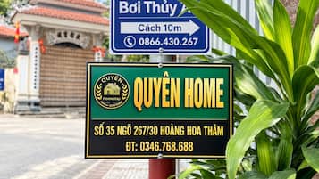 Ein Schild für 'Quyen Home' mit Kontaktdaten und ein Schild in der Nähe für ein 'Baby Care Center'.