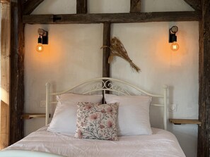 A bed with a white headboard, two wall-mounted light fixtures, and a decorative wall piece. - Les Châtaigniers Vacation Rental - CAME (CAME)
