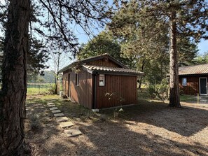 A wooden cabin with a tiled roof, surrounded by trees and a gravel path. - Les Châtaigniers Vacation Rental - CAME (CAME)