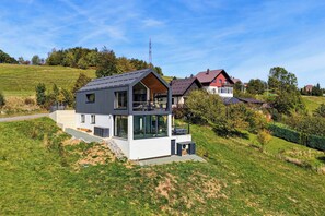 A modern two-story house with a balcony, situated on a grassy hillside. - Forest Peak Retreat with Indoor Pool and Sauna, Ravna Gora, Croatia (Ravna Gora)