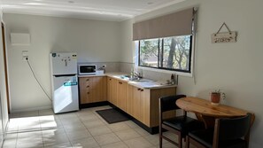 Eine kleine Küche mit Kühlschrank, Mikrowelle, Spüle und Holzschränken.