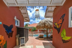 Un espace extérieur abrité doté d’une piscine, d’un toit de chaume et de peintures murales représentant des papillons.