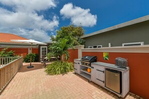 An outdoor patio with a barbecue grill, a small refrigerator, and a table with chairs. - Studio Sea by Casa Lou Lou modern central location with shared pool (Noord)