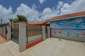 Ein von einer Mauer umgebenes Anwesen mit einem Wandbild von Flamingos und einer Strandansicht.