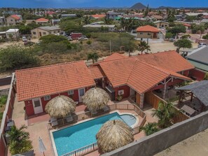 Zona residencial con piscina, casas de techo rojo y construcciones con tejados de paja.
