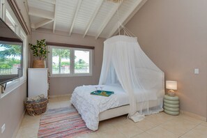 Un dormitorio con cama, lámpara de noche, ventana y vistas al exterior.