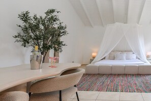 A bedroom with a bed under a white canopy, a bedside table with a vase and a candle, and a large plant in the corner. - Studio Palm by Casa Lou Lou- modern  with shared pool- central location (Noord)