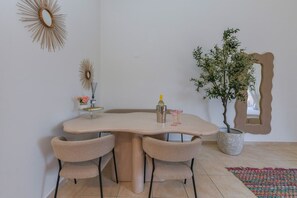 A dining area with a round table, four chairs, a potted plant, and a mirror on the wall. - Studio Palm by Casa Lou Lou- modern  with shared pool- central location (Noord)