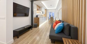 A modern living room with a sofa, TV, and a dining area in the background. - 2BR/2BA Apartment Next to Gran Vía Berlany España (Madrid)