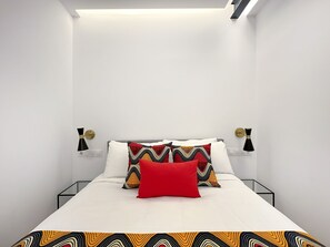 A modern bedroom with a bed, white bedding, and patterned pillows. - 2BR/2BA Apartment Next to Gran Vía Berlany España (Madrid)