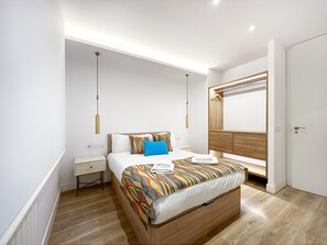 Ein modernes Schlafzimmer mit Bett, Nachttischen, einem Kleiderschrank und einer Pendelleuchte.
