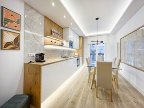 A modern kitchen with a glass dining table, wooden accents, and artwork on the walls. - 2BR/2BA Apartment Next to Gran Vía Berlany España (Madrid)