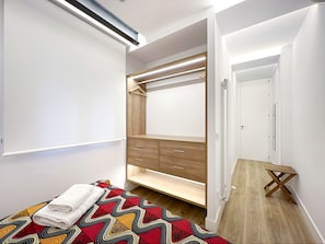 Un dormitorio con cama, mesita de noche, armario y vestidor.