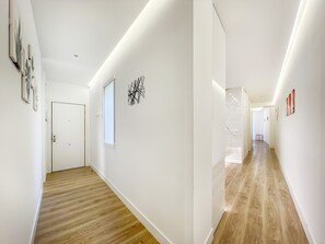 Ein moderner Flur mit Holzboden, weißen Wänden und einer Deckenleuchte.
