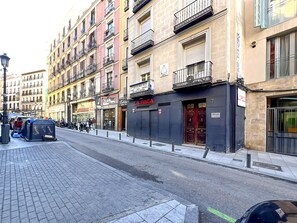 A street with multi-story buildings, one with a closed shutter and a sign that reads 'LA PACA.' - Spacious 2BR/2BA Close Plaza España Berlany España (Madrid)