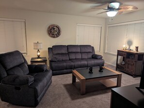 Una sala de estar con un sofá, una mesa de centro, una lámpara y un reloj decorativo en la pared.