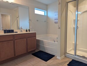 Un baño moderno con un espejo grande, una bañera y una zona de ducha.