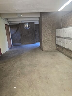 Eine Parkgarage mit Schließfächern rechts, einer Tür links und einem Betonboden.
