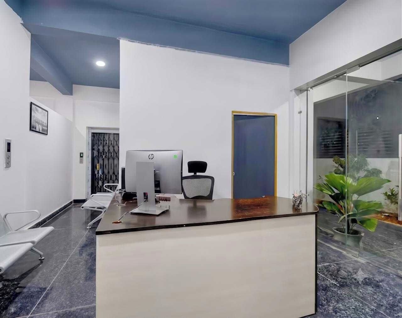 A reception desk with a computer, a chair, and a door in a modern office space.