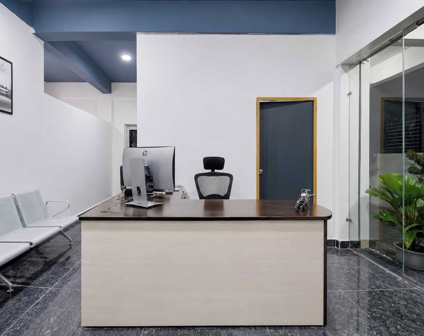 Un mostrador de recepción con una computadora, una silla y una puerta.
