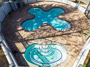 Ein Swimmingpool mit einem einzigartigen Wellendesign, umgeben von einer Ziegelterrasse.