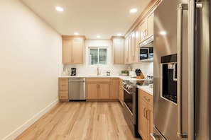A modern kitchen with wooden cabinets, stainless steel appliances, and a window above the sink. - Ski-in/ski-out 3BR condo with resort amenities and slope views. (Park City)