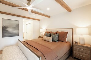 A bedroom with a bed, bedside lamps, a ceiling fan, a painting, and a wooden headboard. - Ski-in/ski-out 3BR condo with resort amenities and slope views. (Park City)