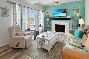 A living room with a fireplace, a television, and a sofa. - Madeira Beach Yacht Club Condo with Heated Pool, Marina, Beautiful Grounds and Easy Beach Access (Madeira Beach)
