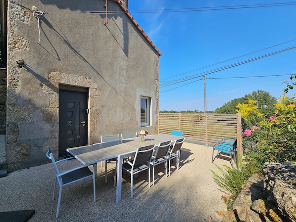 Un patio con una mesa, sillas, una puerta y una ventana.