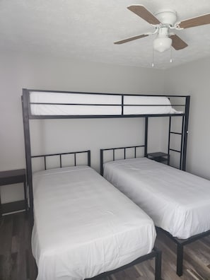 Ein Stockbett mit Deckenventilator in einem Zimmer mit Holzboden.