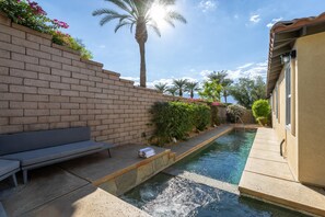 A swimming pool with a brick wall, a bench, and a palm tree. - For Shore | Private Pool & Spa | Fire pit | Rancho Mirage (Rancho Mirage)