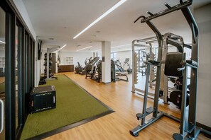A gym with various exercise equipment, a green mat, and weightlifting machines. - Downtown Cincinnati | Free Parking, Pool & Gym (Cincinnati)