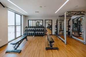 A gym with weightlifting equipment, benches, and dumbbells. - Downtown Cincinnati | Free Parking, Pool & Gym (Cincinnati)